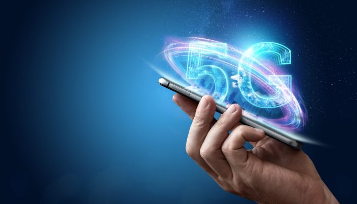 Creative background, male hand holding a phone with a 5G hologram on the background of the city. The concept of 5G network, high-speed mobile Internet, new generation networks. Copy space, Mixed media.