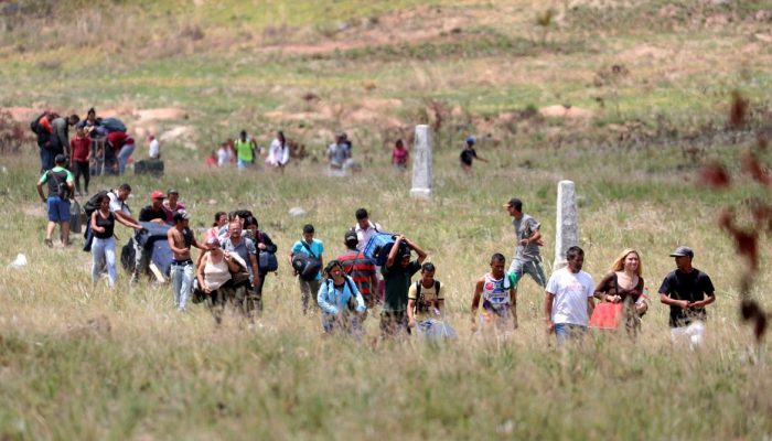 Pessoas caminham para tentar atravessar a fronteira entre a Venezuela e o Brasil em Pacaraima.