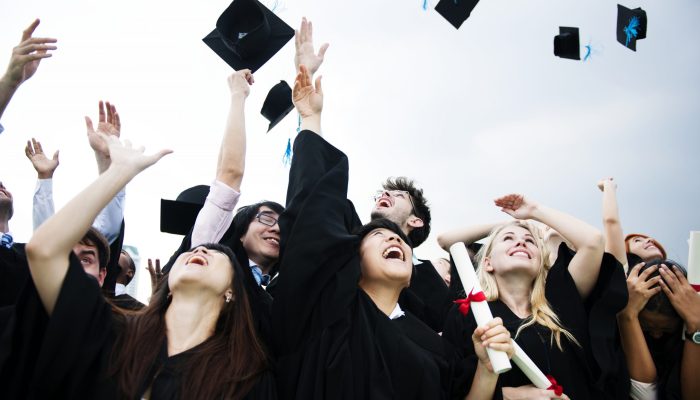 Group of diverse grads throwing caps up in the sky