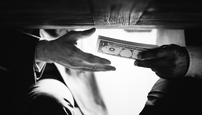 hands-passing-money-table-corruption-bribery