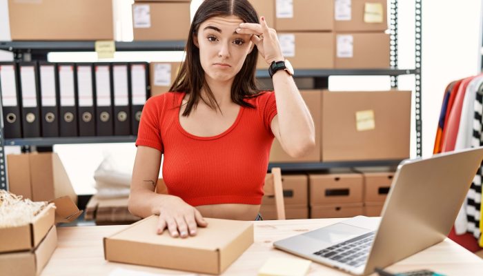 Young hispanic woman preparing order working at storehouse worried and stressed about a problem with hand on forehead, nervous and anxious for crisis