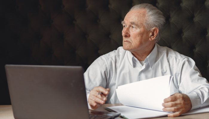 old-man-sitting-table-working-with-laptop
