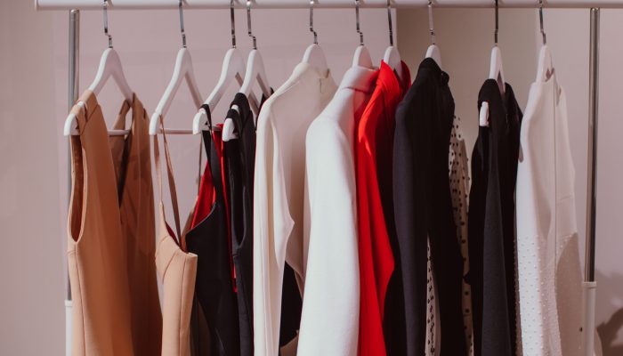 Designer fashion outfits hanging in a row at the backstage. Beige, white, red colors. Spring summer fashion collection