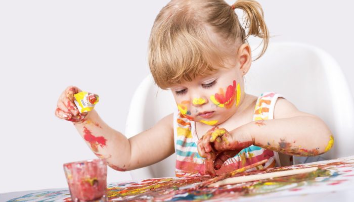 A selective focus shot of a little girl painting and playing