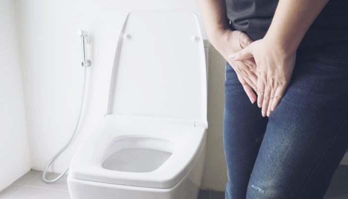 Woman holding hand near toilet bowl - health problem concept