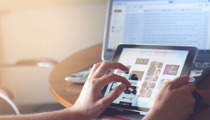 woman-using-digital-tablet-with-laptop-in-background