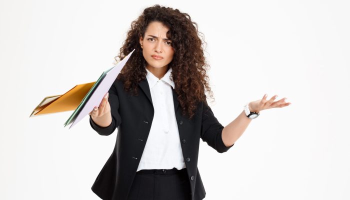 Young confused curly girl holding documents over white background